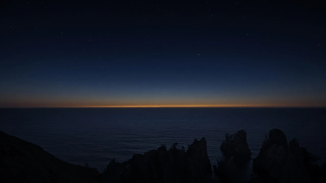 Sea cliffs before dawn, thin gold light on the horizon